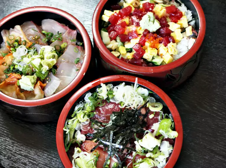 Die Japanischen Spezialitäten müssen Sie unbedingt genießen Drei Schüsseln mit verschiedenen japanischen Gerichten auf dunklem Holztisch.