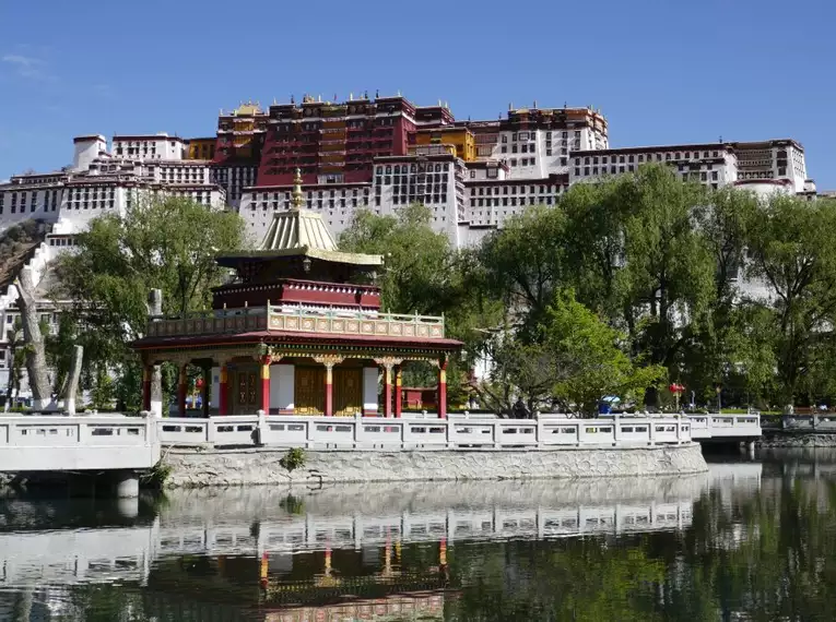 Potala-Palast in Tibet mit reflektierendem See im Vordergrund.