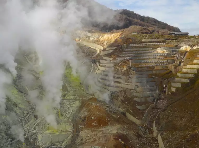 Dampfende Erdspalten im Hakone-Krater Hakone-Krater mit dampfenden Erdspalten und terrassierten Hängen.