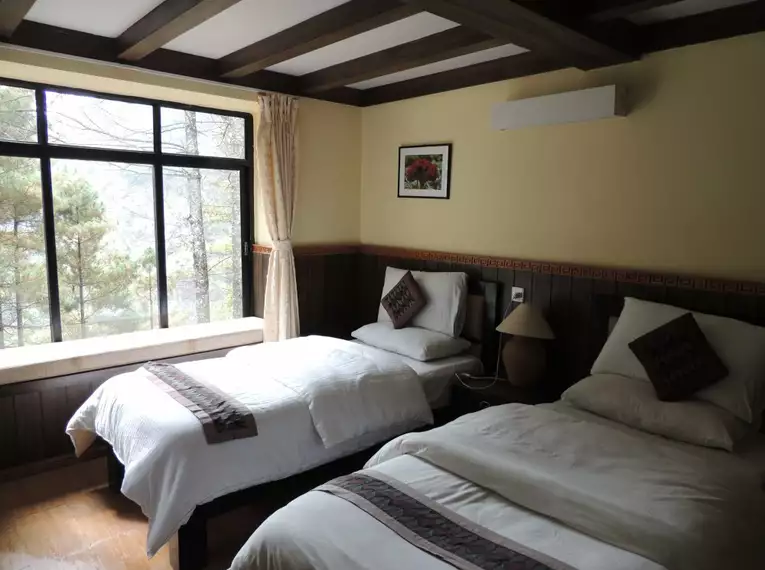 Zimmer mit zwei Betten und großem Fenster in einer Lodge im Himalaya