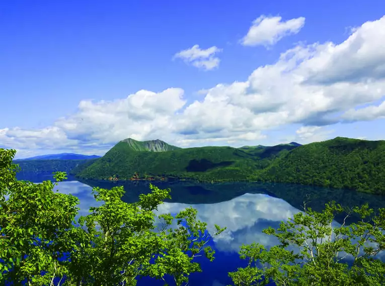 Beeindruckender Blick auf den Mashu-See Panorama des kristallklaren Mashu-Sees, umgeben von grünen Bergen und blauem Himmel in Japan.