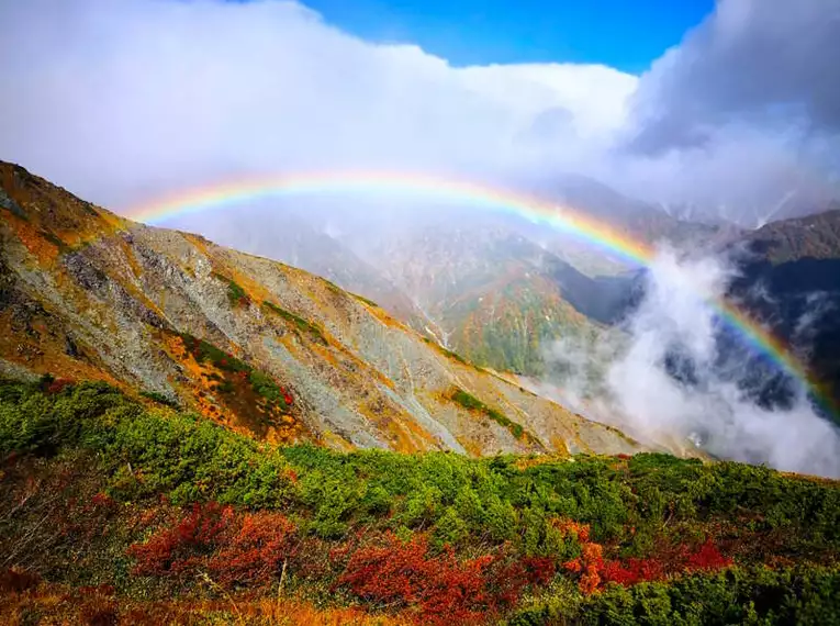 Regenbogen über den Japanischen Alpen Blick auf Regenbogen über den bewaldeten Bergen der Japanischen Alpen