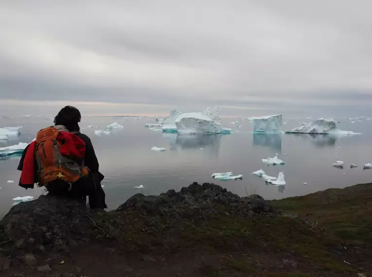 Blick auf Eisberge in Grönland Person mit Rucksack betrachtet Eisberge im Wasser, Grönland.