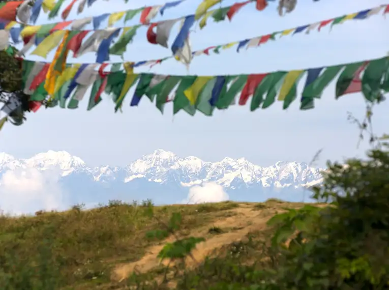 Schneebedeckte Himalaya-Berge mit bunten Gebetsflaggen im Vordergrund.