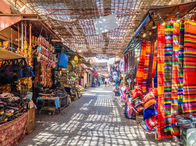 Bunte Marktstände in Marrakesch, gefüllt mit Stoffen und Handwerkskunst.
