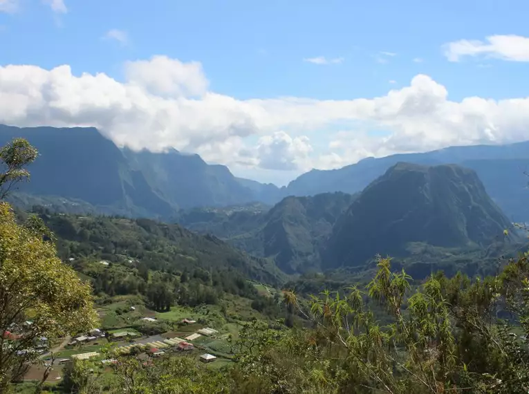 Blick auf die majestätischen Berge und Täler von La Réunion unter einem klaren blauen Himmel.
