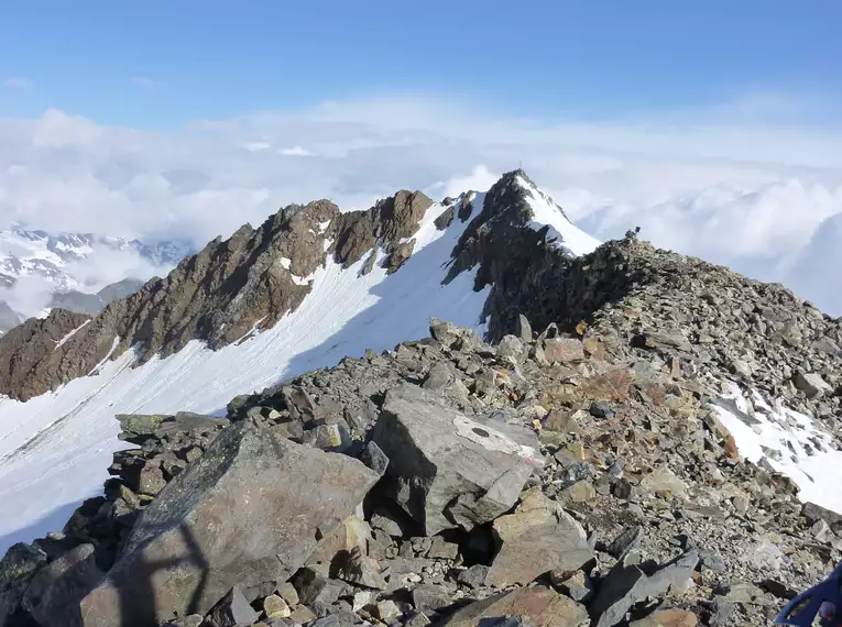 Blick vom Gipfel in den schneebedeckten Stubaier Alpen unter blauem Himmel.