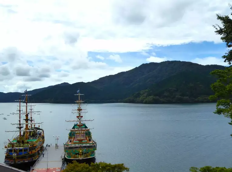 Boote auf dem Ashi-See in Japan Zwei Boote auf dem Ashi-See vor bewaldeten Hügeln in Japan