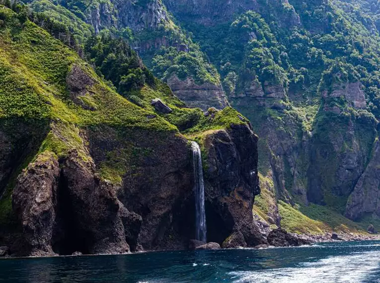Küste von Hokkaido: Faszination der Natur Felsige Klippen mit Wasserfall an Hokkaidos Küste im Shiretoko Nationalpark.