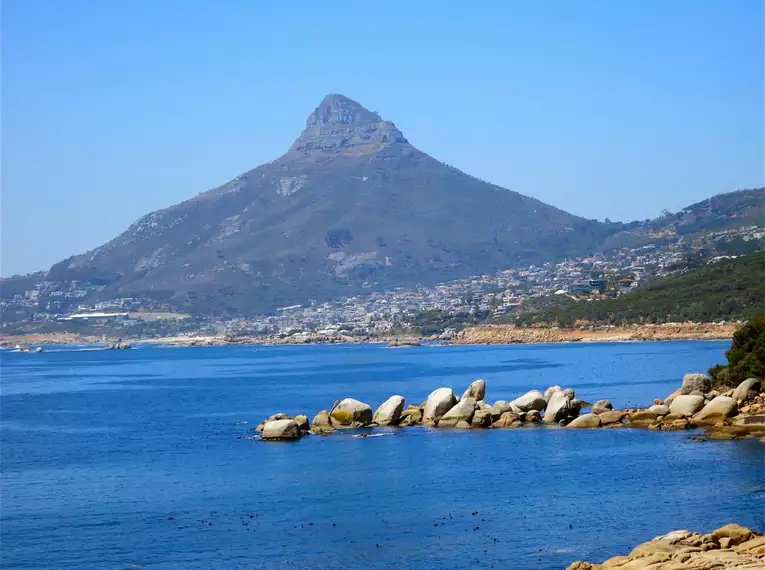 Blick auf einen markanten Berg und die Küstenlinie vor einem blauen Himmel in Südafrika.
