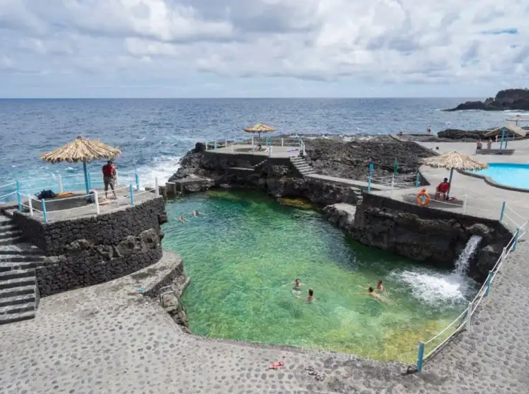 Mehrere Menschen schwimmen in den natürlichen Meeresbecken von La Palma.