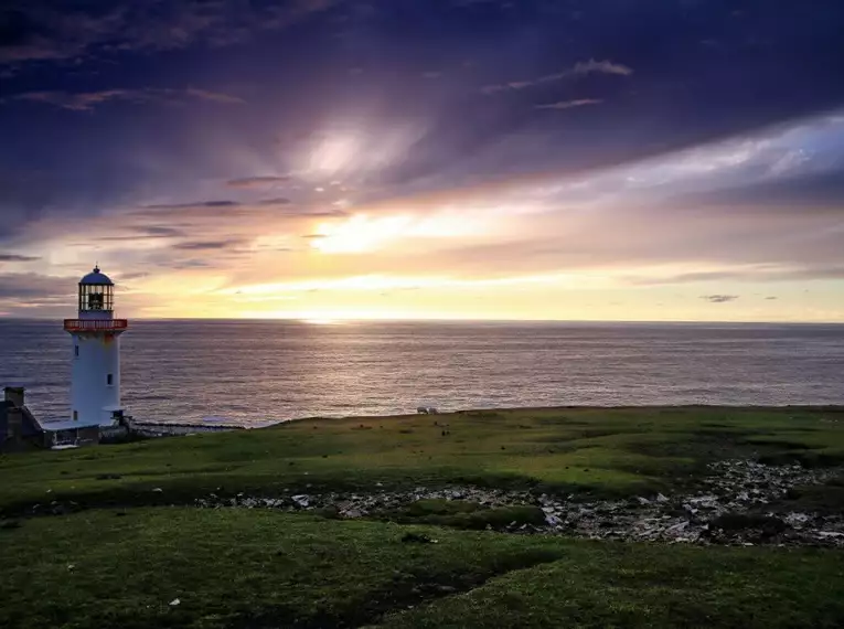 Leuchtturm an der irischen Küste bei Sonnenuntergang Landschaftsbild von einem Leuchtturm am Meer mit Sonnenuntergang in Irland.