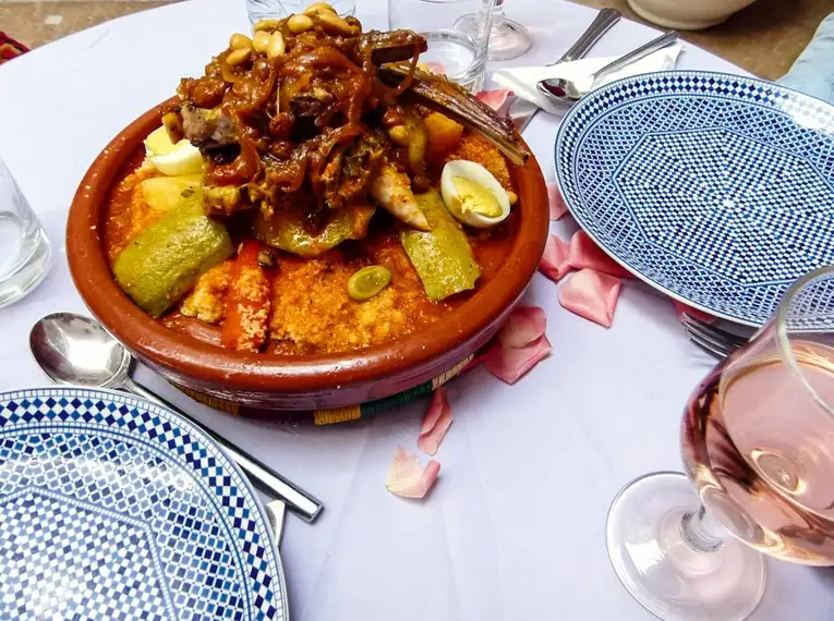 Traditionelle marokkanische Tajine Marokkanische Tajine mit Gemüse und Fleisch auf einem Tisch mit Geschirr und Weinglas.