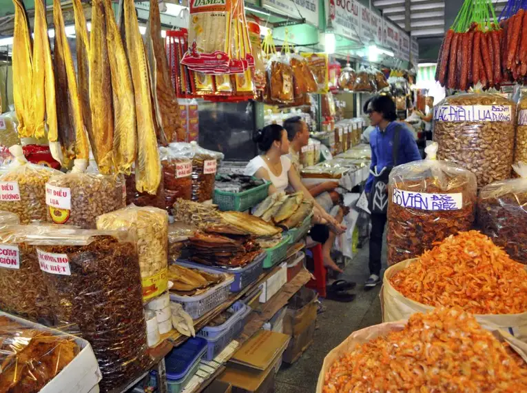 Ein geschäftiger vietnamesischer Marktstand mit getrockneten Lebensmitteln und lokalen Verkäufern.