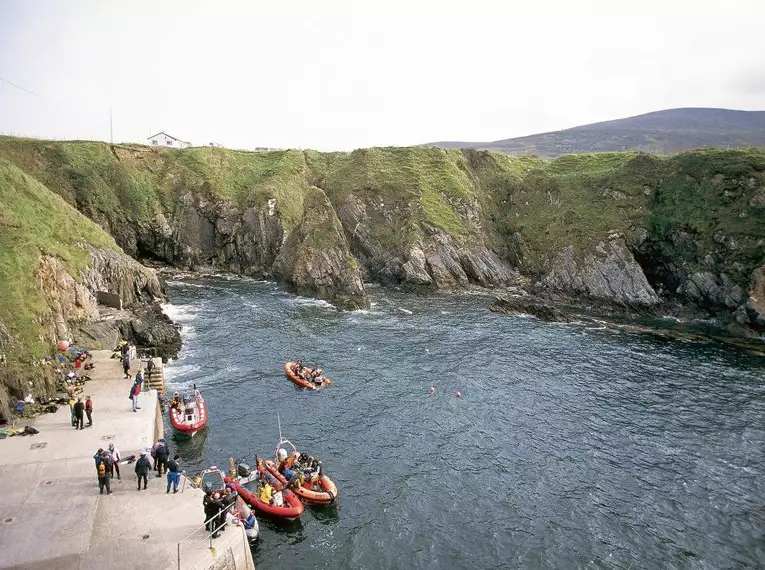 Küste von Arranmore Island Boote und Menschen an der felsigen Küste von Arranmore Island, Irland.