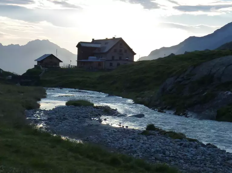 Idyllische Berglandschaft mit Franz Senn Hütte und Fluss bei Sonnenuntergang in den Stubaier Alpen.