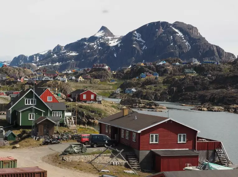 Malerisches Dorf auf Grönland Bunte Häuser vor schneebedeckten Bergen in Grönland.