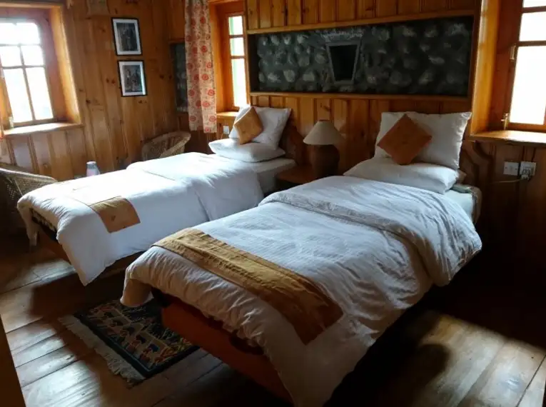 Ein gemütliches Zimmer in einer Lodge mit zwei Betten, Holzwänden und Fenstern.