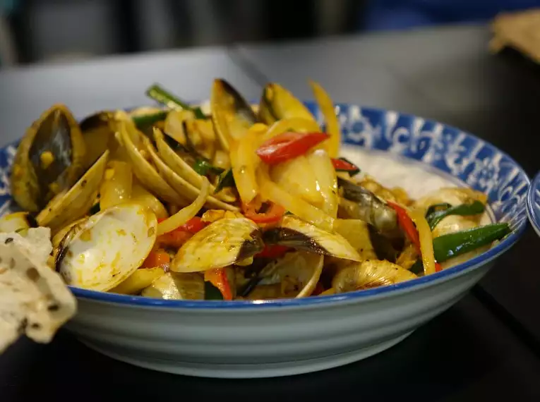 Vietnamesische Küche genießen Ein traditionelles vietnamesisches Gericht mit Muscheln und Gemüse auf einem Tisch.