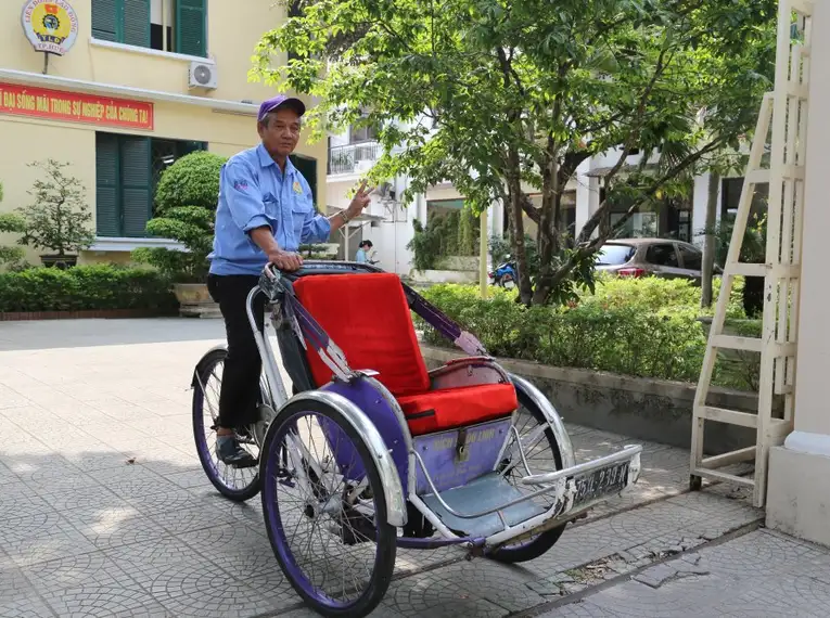 Ein Mann fährt eine traditionelle Rikscha in Vietnam.