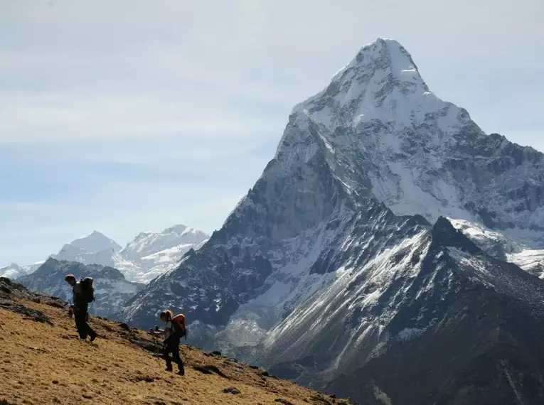 Zwei Wanderer vor einer beeindruckenden, schneebedeckten Bergkulisse in Nepal.