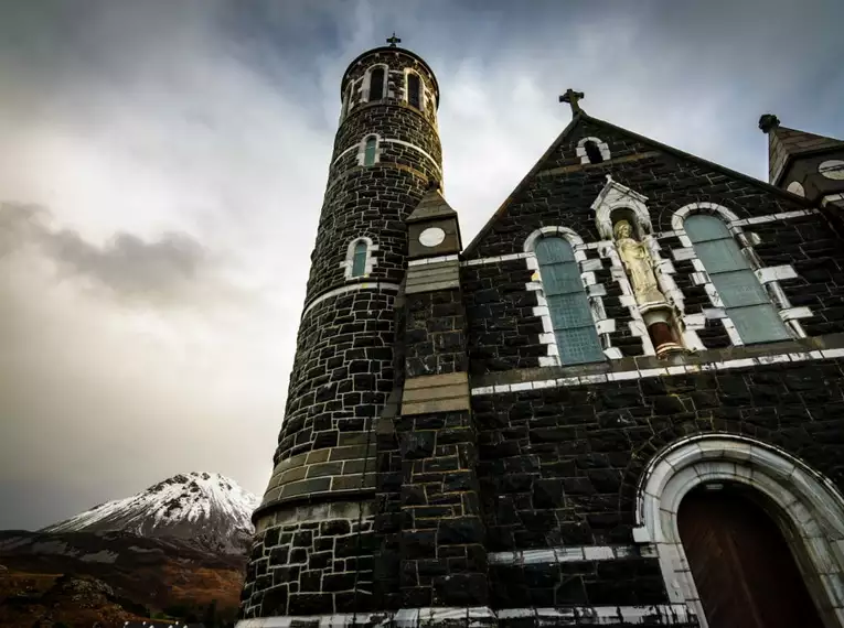 Historische Kirche entlang unseres Weges Eindrucksvolle Kirche vor dramatischer Berglandschaft in Irland